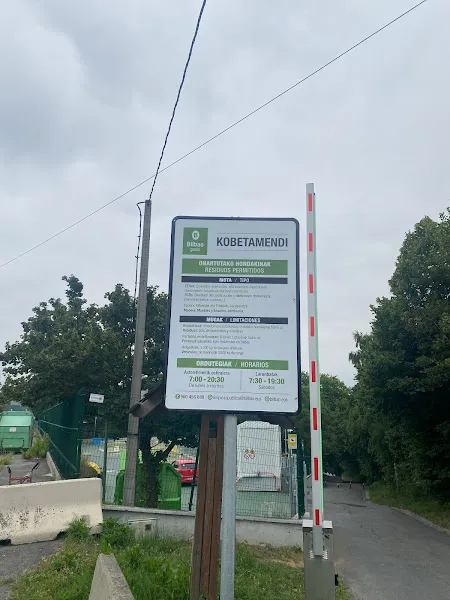 Cartel informativo y barrera de entrada del centro de reciclaje bilbogarbi kobetamendi con contenedores verdes