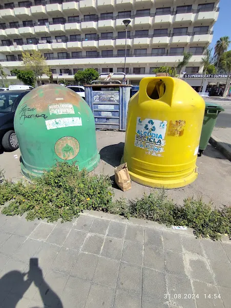Iglú amarillo y verde junto a contenedor de papel de vidrio en una acera urbana