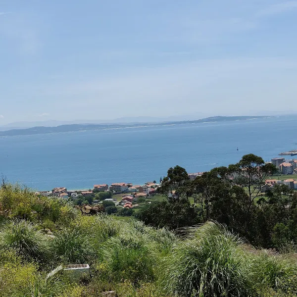 Panorámica costera sobre el punto limpo ribeira con casas, colinas verdes y mar azul