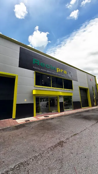 Fachada de nave industrial con rótulo de reciclados industriales de pravia s l y marcos amarillos en puertas y ventanales